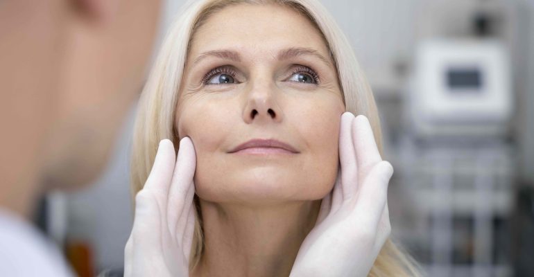 Close-up of a smiling middle-aged woman during aesthetic consultation, representing Metoo dermal filler volume assessment